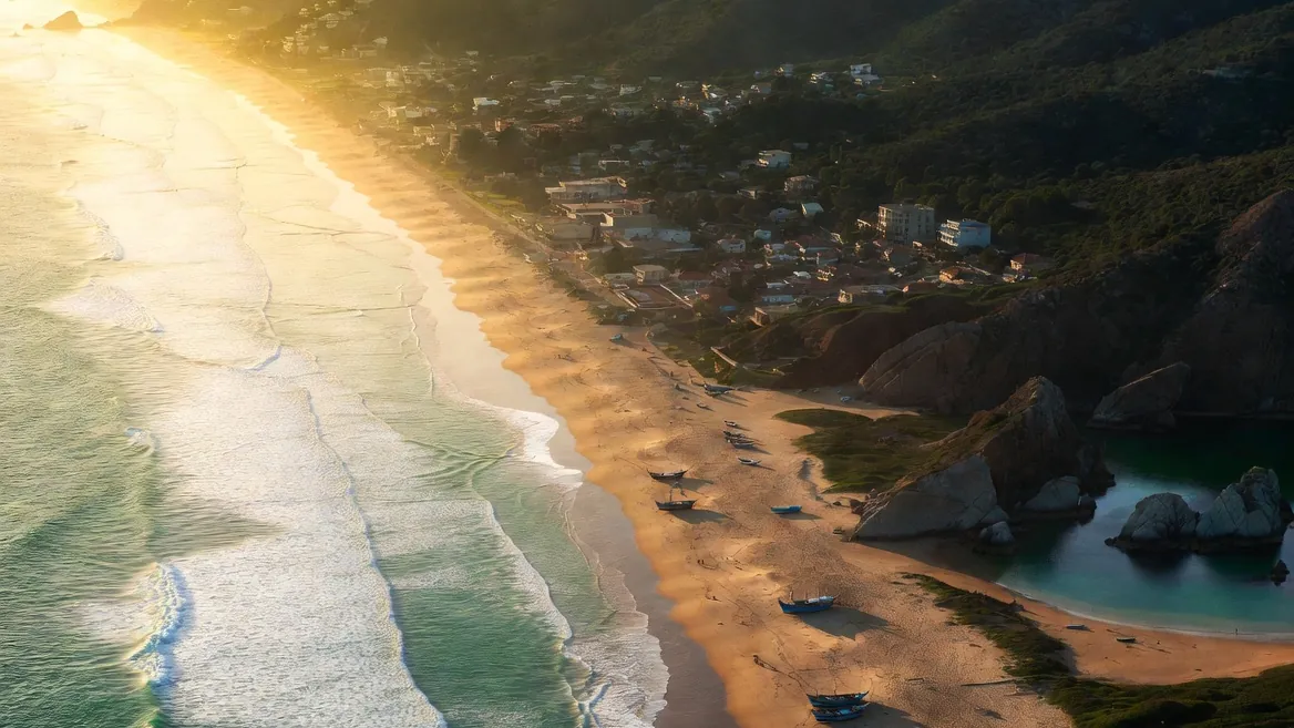 Aerial view of the Puerto Escondido coastline at golden hour, with Zicatela's surf beach and rocky coves beyond